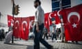 A man walks by flags picturing the face of Atatürk during a protest.