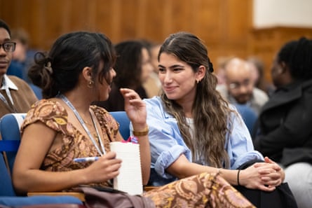 a woman smiles while seated next to another woman