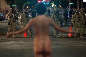 A nude protester faces off against Federal law enforcement officers in Portland on Saturday night