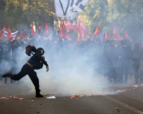 A masked protester throws an object amid clashes with French police in paris.