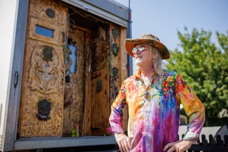 Glen Michael Herbert next to a carved wooden caravan