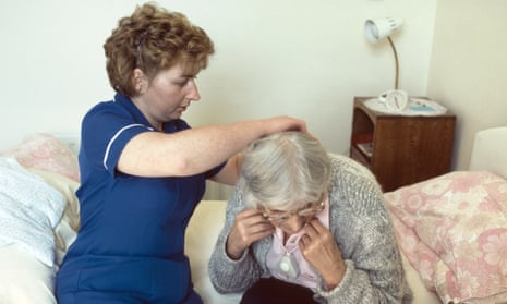 A district nurse assists a patient at home.