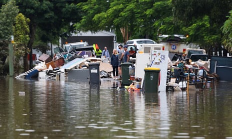 Brisbane residents look on as rubbished is piled up on the a flooded street