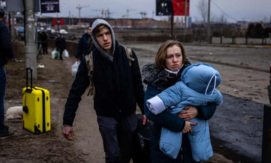 A woman carries her child as they flee the city of Irpin, north-west of Kyiv, Ukraine.