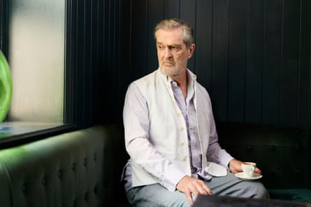 Everett at a banquette with a cup of tea on his knee