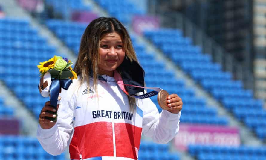 Sky Brown in Team GB tracksuit holds up the bronze medal around her neck for the cameras