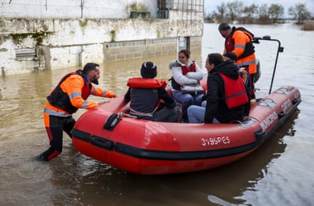 Rescue workers push a red dinghy with three people onboard