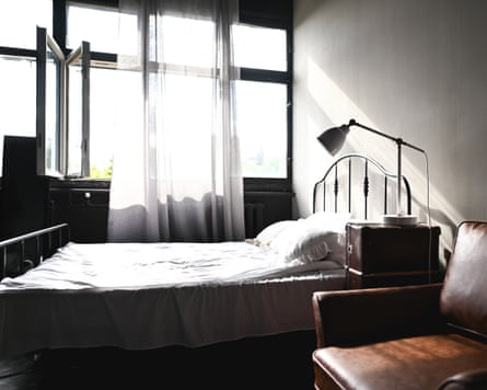 Sunlit bedroom with a bed, open window, and leather armchair