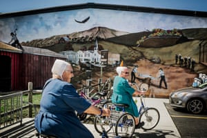 Deux femmes passent devant une peinture murale représentant l'idéal de la vie amish chez elles.