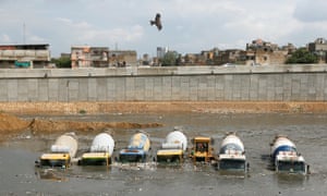 Concrete mixers submerged in flood waters in Pakistan. Profits in the building industry could be affected by higher carbon pricing.