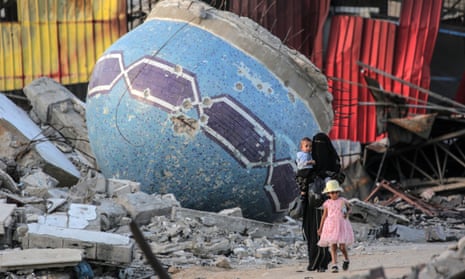 A Palestinian woman and children walk past the remnants of a mosque in Khan Yunis.