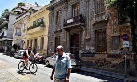 People pass a neoclassical building for sale in one of the oldest districts of Athens.
