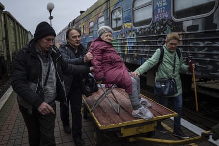 Relatives of Elizaveta, 94, transport her by a cargo cart to an evacuation train in Kherson, 1 December.