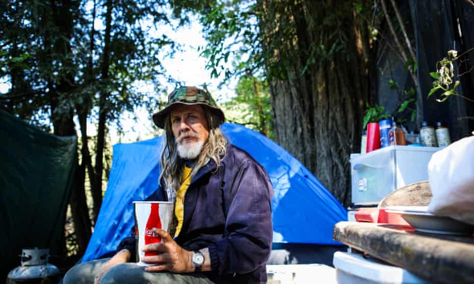 Shawn Whiting, 56, sits in his tent encampment in the woods.