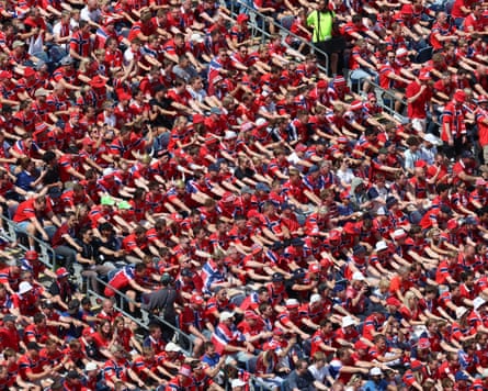 A stand full of Norway supporters wearing red doing the Viking row in their seats
