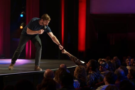 a man on stage interacts with an audience member by fist bumping them