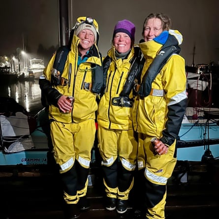 Three women in full yellow sailing waterproofs, Team Sail Like A Mother at the finish line in Ketchikan.