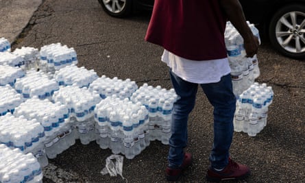 A person unloads packs of bottled water