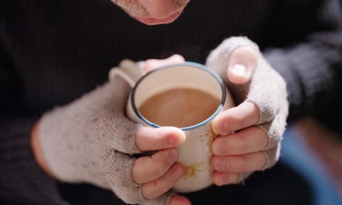 Hands in fingerless gloves holding a cup of tea.