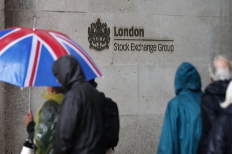 Commuters walk past the London Stock Exchange in the City of London today, as the rain pelted down
