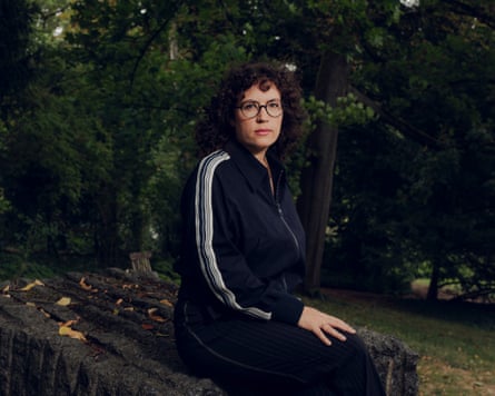 Isabella Weber sits on a carved rock in green gardens surrounded by tall, mature trees