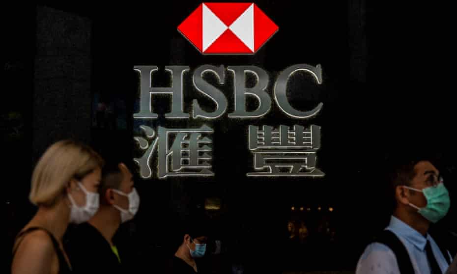 pedestrians walking past the logo for HSBC in Hong Kong