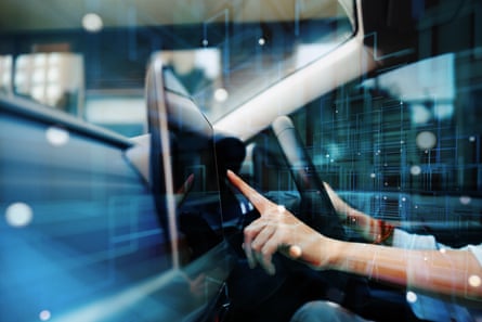 A person’s hands at the wheel of a smart-driving car, while also using a touch display screen in the vehicle