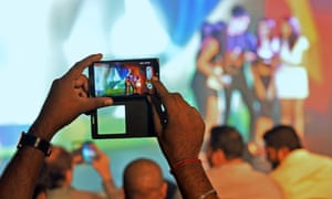 A man films models on his mobile phone