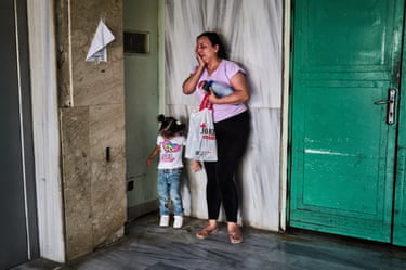 A woman wipes tears from her eyes as she stands by a doorway of a room with her daughter