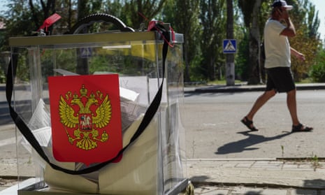 A man walks past a ballot box with Russia’s coat of arms during early voting in Mariupol, Russian-controlled Ukraine