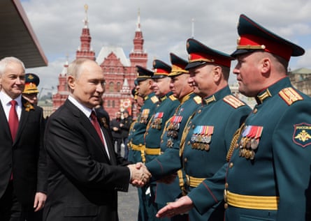 Vladimir Putin shaking hands with a soldier.
