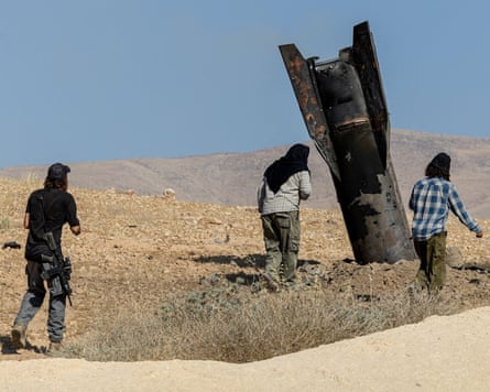 Israeli settlers stand next to part of a missile protruding from the ground after strikes from Iran in the occupied West Bank on Monday.