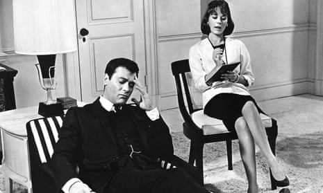 A scene from in Sex and the Single Girl (1964) with Tony Curtis reclining on a couch, one hand touching his temple, his eyes closed, and Natalie Wood sitting on a chair slightly behind him, legs crossed, writing in a notebook.