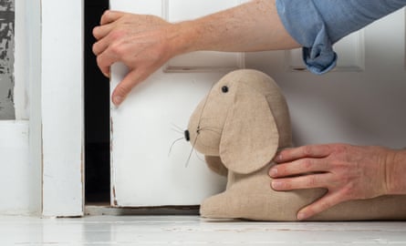 Person putting a dog-shaped draught excluder in front of a door.