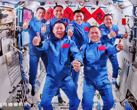 The three astronauts from the Shenzhou-21 spaceship pose with the Shenzhou-20 crew aboard the space station