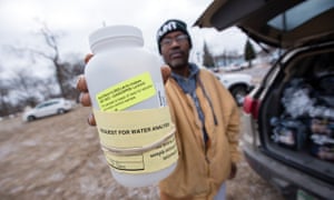 A Michigan resident shows a water testing kit outside a water distribution location in Flint.