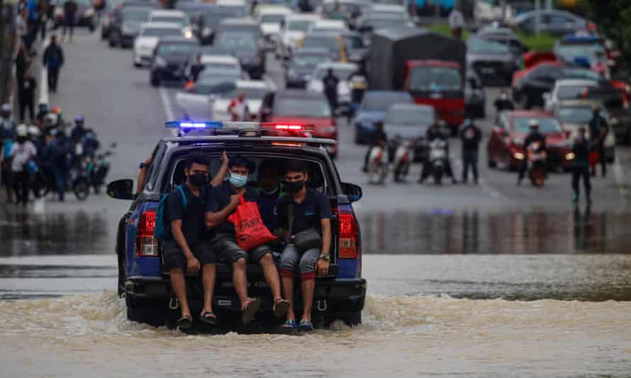 一辆警车载着人们穿过马来西亚首都附近被洪水淹没的高速公路。