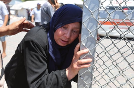 A woman cries as she clutches a metal fence