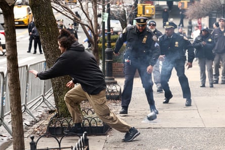 a man runs toward a barricade as an improvised explosive device emits smoke on the ground as police move toward it