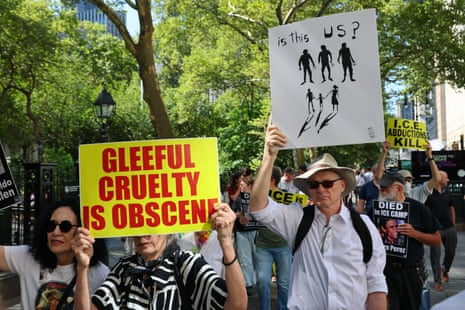 a person holds a sign that reads 'gleeful cruelty is obscene'