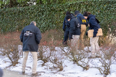 People in blue coats and no hats look down as they walk in snow, looking for something.