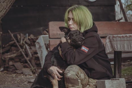 A woman sits cuddling a large dog.