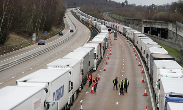 People walk alongside lines of lorries queueing at the M20 motorway near Ashford.
