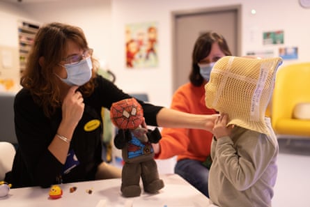 nurse with mask putting mask on child in hospital
