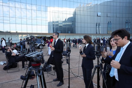 Tripods and mics with media around and mirrored building in background