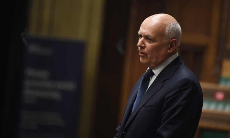 Iain Duncan Smith standing and speaking in a room against an underlit background
