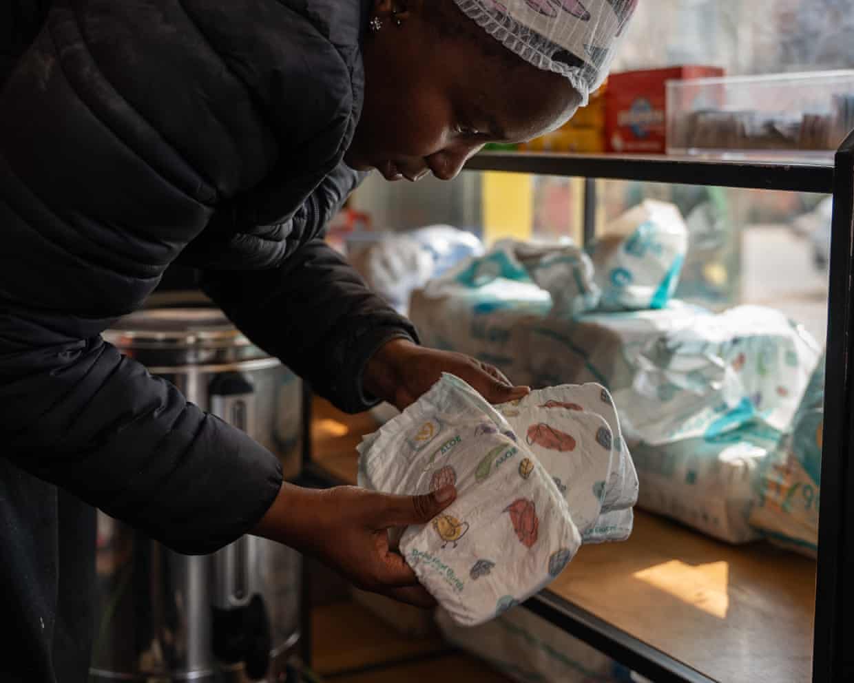 An African woman bends over a counter as she counts nappies