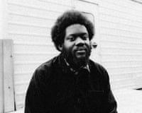 Black and white photo of Michael Kiwanuka, with afro and beard, wearing a dark jacket