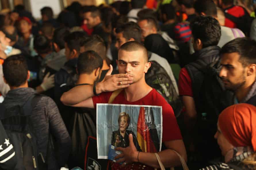 A migrant from Syria holds a picture of Angela Merkel