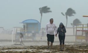 A couple walks along the beach during a downpour on Sunday in Miami.